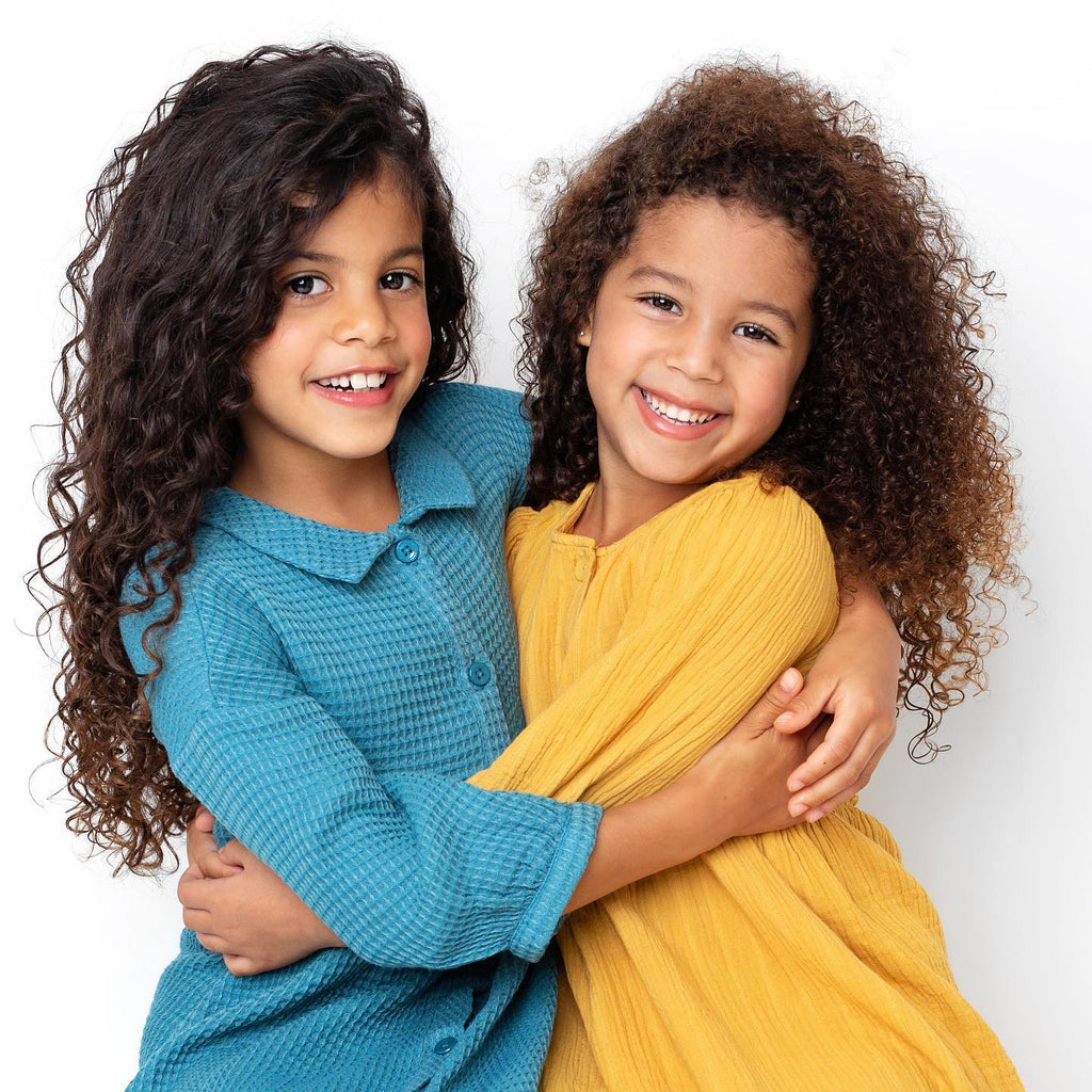 Two girls with curly hair hugging