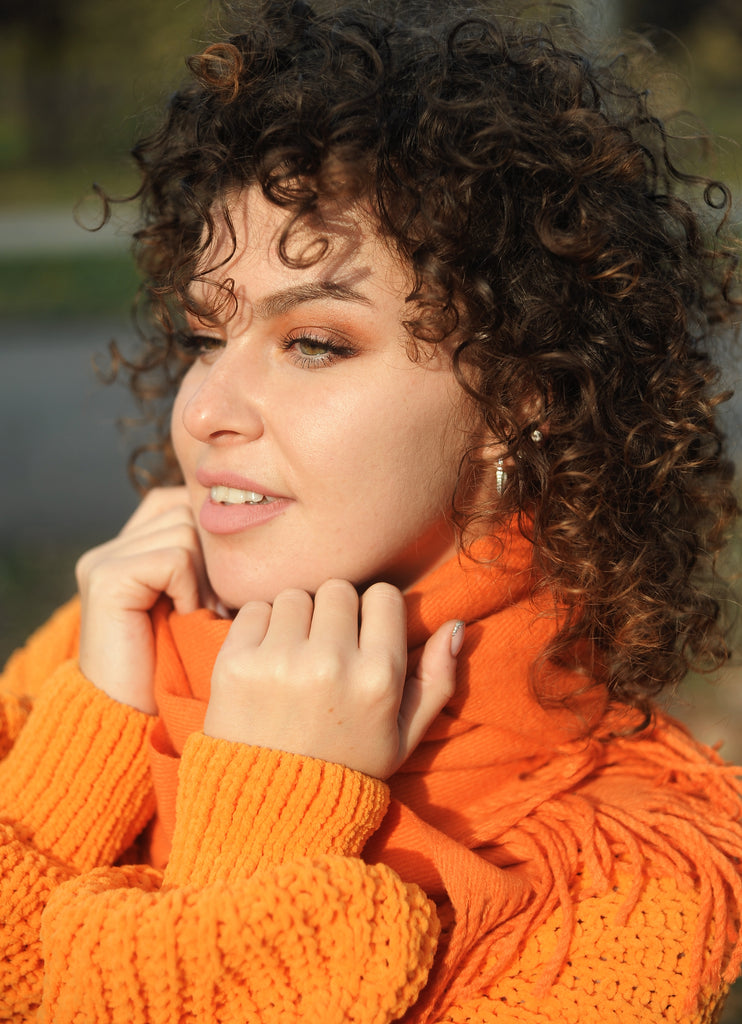 Curly hair woman in orange sweater outside