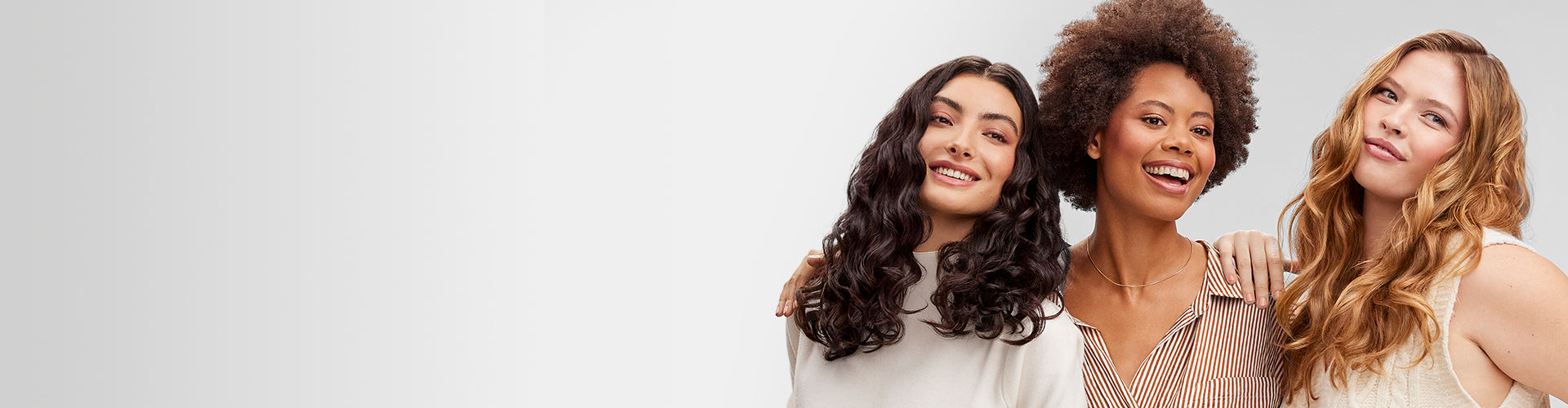 Models with loose curly hair, spiral curls and wavy hair smiling side by side on great background