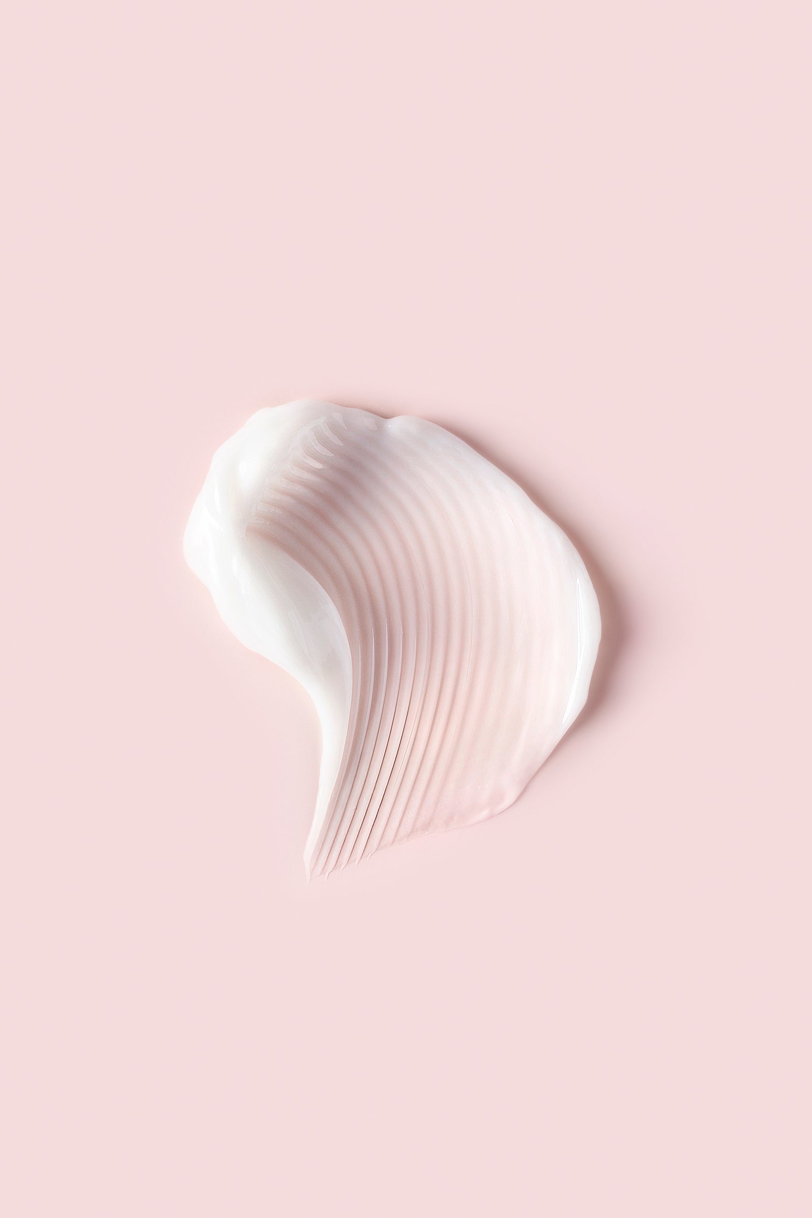 Portion of Advanced Climate Control® Defrizzing Conditioner on pink background